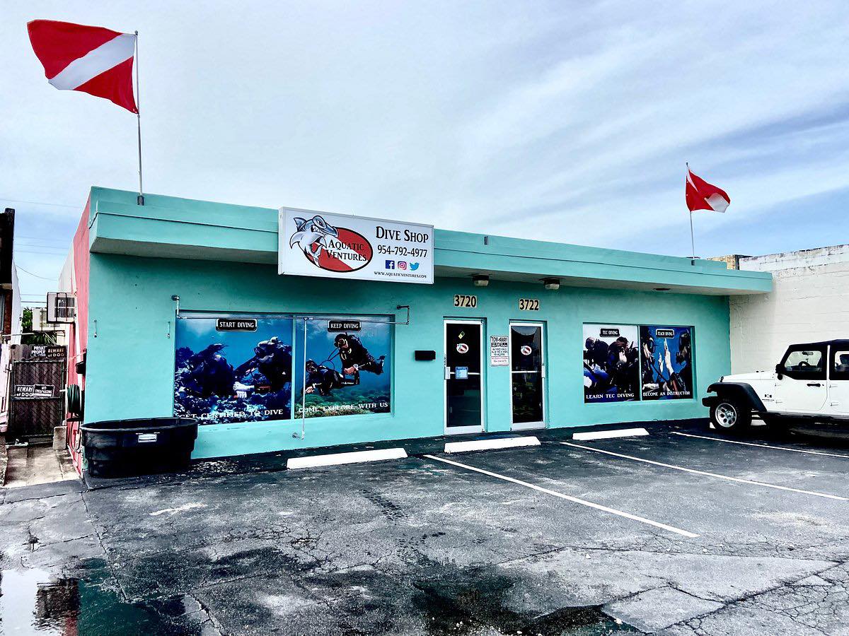 Teal building with dive shop signage and flags on a cloudy day